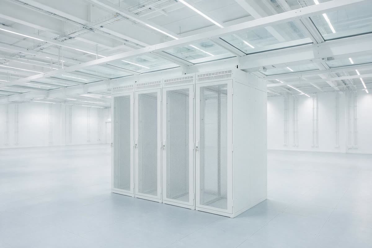 A single compact group of four white server cabinets standing together in an otherwise empty data hall.